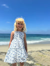 A smiling girl modeling the Sloane dress in all over blue nautical boat print 