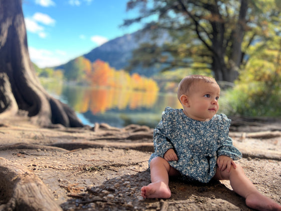 Baby wearing a blue floral bubble onesie outdoors