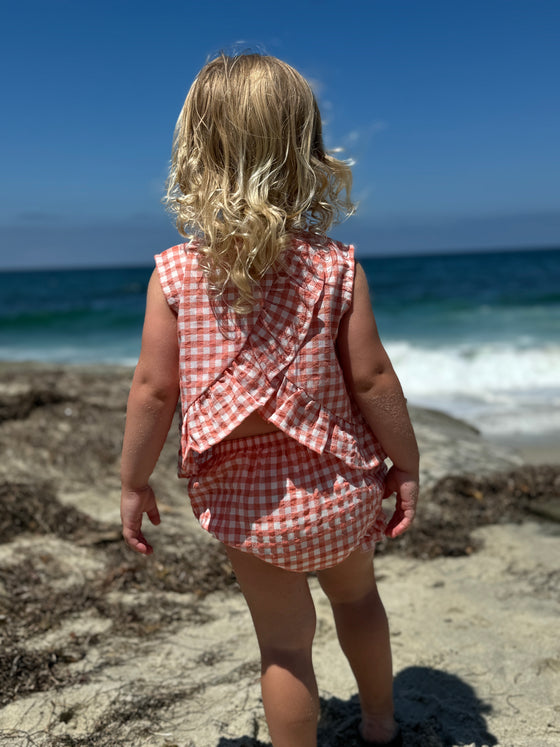Child model wearing Coral Aria Dress with matching bloomer back view showing cries cross ruffle detail