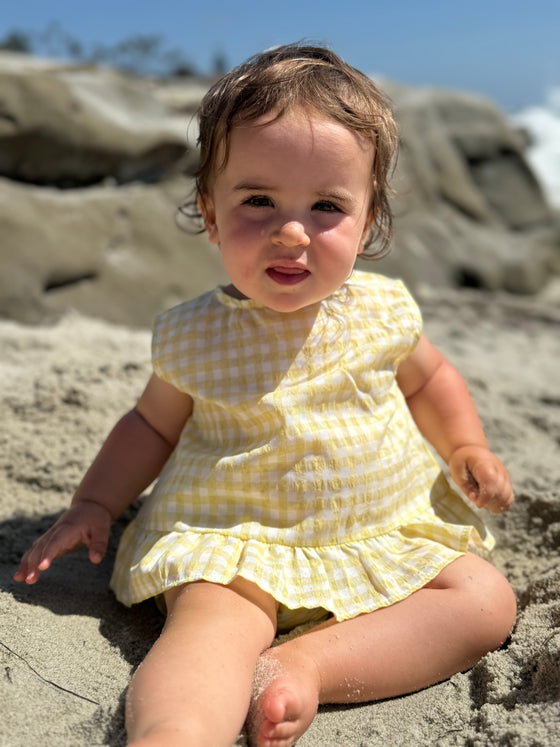 Brown haired child model wearing Yellow Aria Dress with matching bloomer 