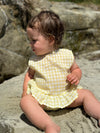 Child model at the beach wearing yellow plaid Aria Dress and matching bloomer 
