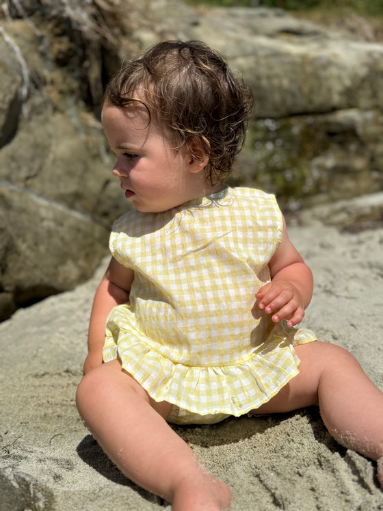 Child model at the beach wearing yellow plaid Aria Dress and matching bloomer 