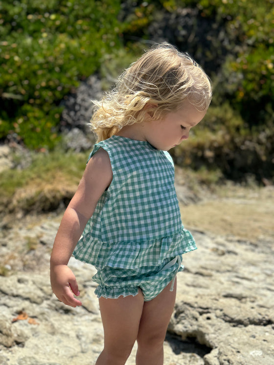 Child model on the beach in Green Plaid Aria Dress with matching bloomer 