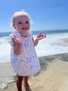 Toddler model at beach wearing Jenn Dress in blue and orange school of fish print 