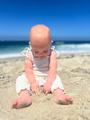 Baby model playing in the sand while wearing blue and yellow striped romper