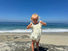 a child model on the beach showing the versatility of the Charlotte Bubble in Green Print Eyelet