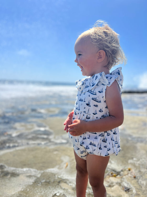 In another moment by the shore, a toddler wears Vignette’s Maya romper with its nautical boat print, creating a picture-perfect blend of comfy style and sunny beach vibes.