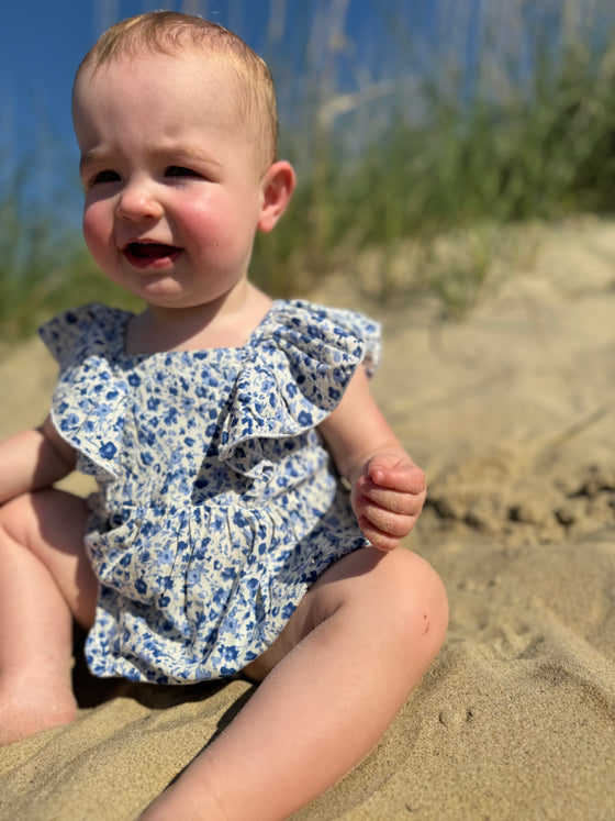Cute baby enjoying a day at the beach while wearing Light blue floral print baby bubble 