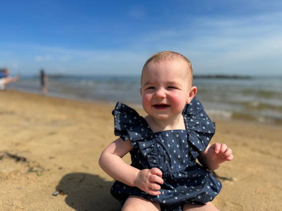 Baby on beach wearing nay blue bubble with all over anchor print 
