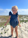 Toddler on beach wearing navy blue anchor print bubble 