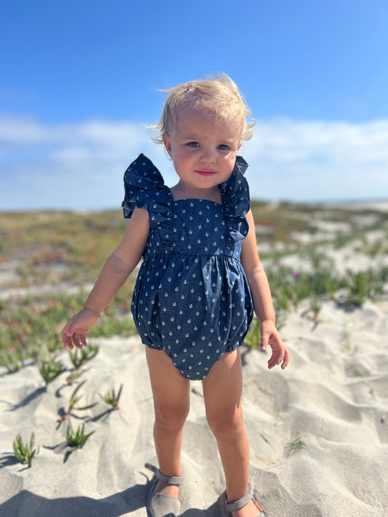Toddler on beach wearing navy blue anchor print bubble 