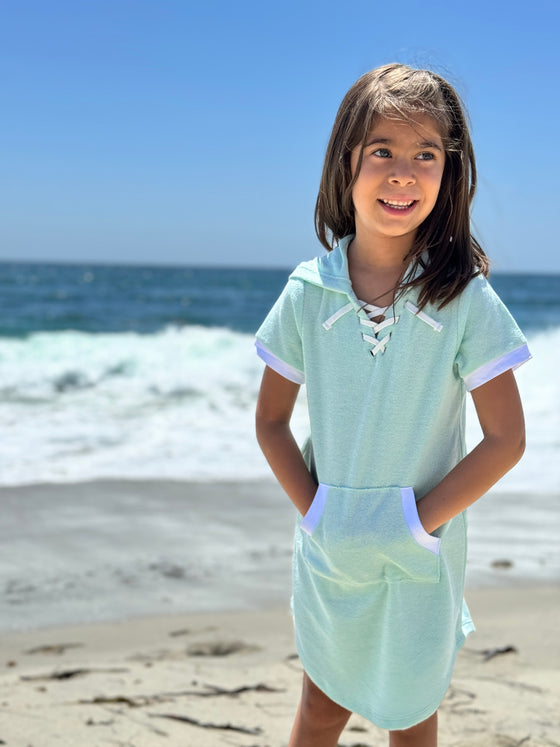 Child model wearing blue Terry cloth  hooded swimsuit cover up on the beach