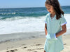 young girl on the beach wearing a blue Terry cloth dress
